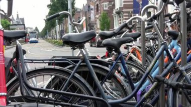 Amsterdam, Hollanda-06 Temmuz 2018: 4K. Amsterdam, Hollanda 'da bir caddeye parketmiş bisikletler. Tramvay yaklaşıyor ve park edilmiş bisikletlerin arkasından geçiyor.