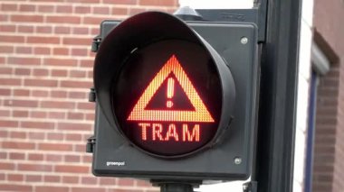 4 bin. Tramvayı geçerken trafik ışığı yanıp sönüyor. Amsterdam, Hollanda 'da bir caddede tramvay tabelası
