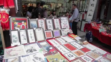 XIAN, Çin - 26 Mayıs 2012: Kimliği belirsiz insanlar Çin 'in Xian kentindeki alışveriş caddesindeki tezgahtan geleneksel hediyeleri seçiyorlar.
