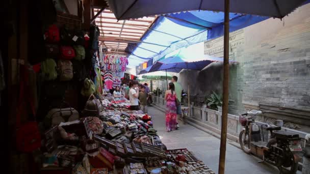 XIAN, CHINA - MAJ 26, 2012: Niezidentyfikowani ludzie wybierają tradycyjne pamiątki na stoisku przy ulicy handlowej w Xian, Chiny. — Wideo stockowe