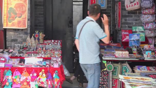 XIAN, Çin - 26 Mayıs 2012: Kimliği belirsiz insanlar Çin 'in Xian kentindeki alışveriş caddesindeki tezgahtan geleneksel hediyeleri seçiyorlar. — Stok video
