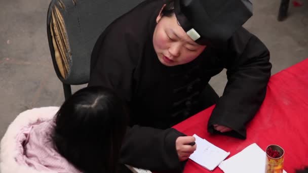 XIAN CHINA - FEB 06 2012: Fortuneteller tell fortunes for a girl in market — ストック動画