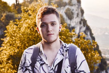 Arka planda dağlar ile yakışıklı bir genç adam Portresi.