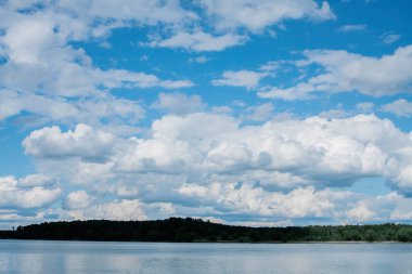 Güneşli bir yaz günü orman kıyısında mavi bir gökyüzünde beyaz bulutlar