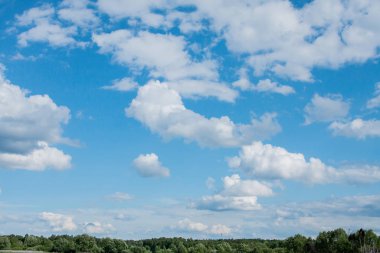 Güneşli bir yaz günü orman kıyısında mavi bir gökyüzünde beyaz bulutlar