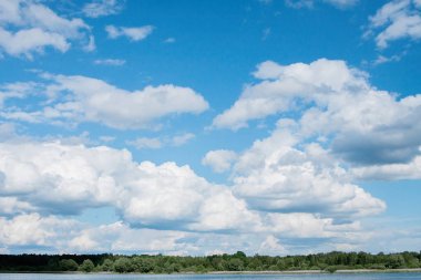 Güneşli bir yaz günü orman kıyısında mavi bir gökyüzünde beyaz bulutlar