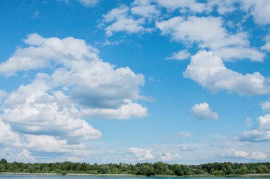 Güneşli bir yaz günü orman kıyısında mavi bir gökyüzünde beyaz bulutlar