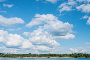 Güneşli bir yaz günü orman kıyısında mavi bir gökyüzünde beyaz bulutlar