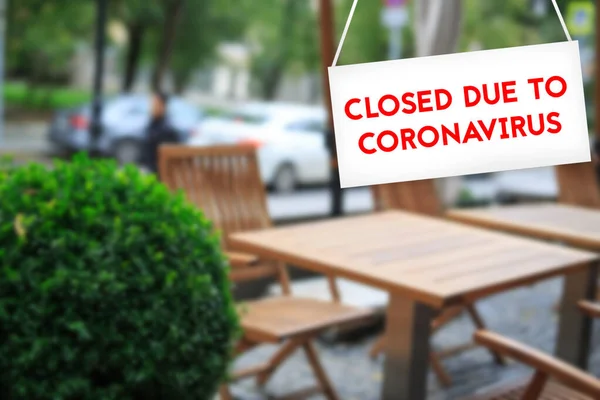 CORONAVIRUS işareti nedeniyle kapalı. Arka planda bulanık bir kafe arka planda beyaz bir arkaplan üzerinde kırmızı harflerle.