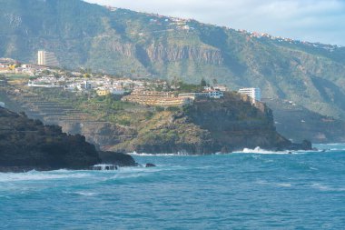 Okyanus kıyısında ve Punta Brava, Puerto de la Cruz, Tenerife, Kanarya Adaları 'ndaki kayadaki renkli binalara bakın.