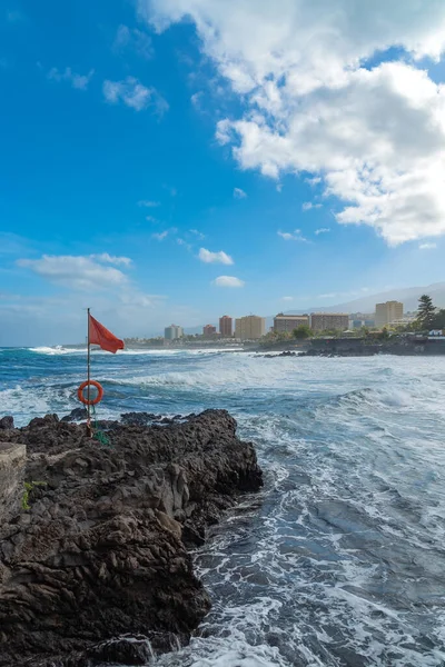 Rote Flagge auf einem Felsen in einer Bucht mit Blick auf Meer und Küste von Puerto de la Cruz, Teneriffa, Spanien — Stockfoto