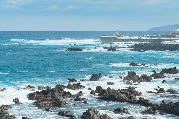 Felsige Küste von Puerto de la Cruz. Wellen des Atlantiks rollen an einem sonnigen Tag über die Felsen, Teneriffa, Spanien — Stockfoto