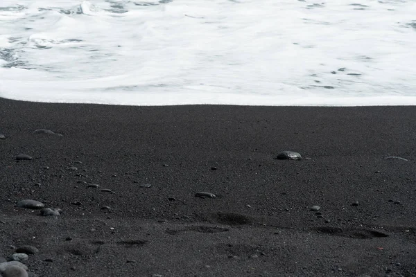 Beyaz köpüklü okyanus dalgaları siyah kumsalda çakıl taşıyla yuvarlanıyor. İpeksi siyah plaj dokusu. Minimalist siyah arkaplan. Tenerife voulcanic kumlu kıyısı. — Stok fotoğraf