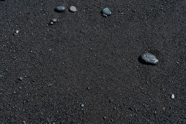 Black sand beach with pebble macro photography. Silky black beach texture. Minimalistic black background. Tenerife voulcanic sandy shore. — Stock Photo, Image