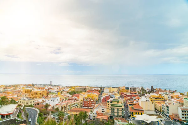 Paisagem da cidade junto ao oceano com um sopro azul com nuvens. Puerto de La Cruz num dia ensolarado. Tenerife, Espanha — Fotografia de Stock