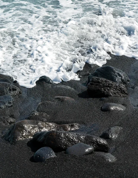 Ozeanische Welle mit weißem Schaum rollt über den schwarzen Sandstrand mit Kieselsteinen. Seidig schwarze Strandtextur. Minimalistischer schwarzer Hintergrund. Teneriffa voulkanische Sandküste. — Stockfoto