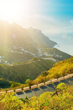 Güneşli bir günde yeşil bitki örtüsü arasında bir dağ tepesinde parlak beyaz küçük binalar. İspanya 'nın Kanarya Adaları, Tenerife Adası' ndaki Taganana köyü