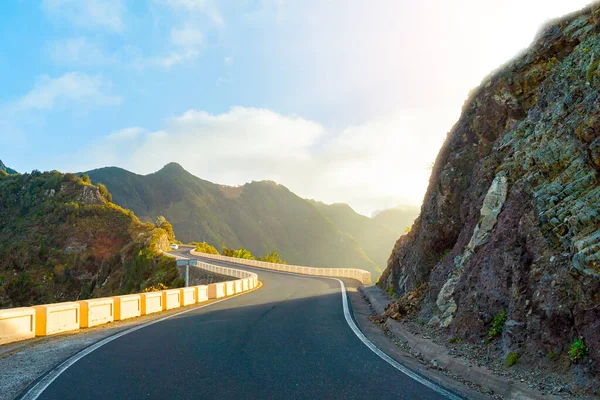 Carretera sinuosa en la cresta de la montaña. Cielo azul con nubes y sol de noche brillante. Parque Rural de Anaga, Tenerife, España — Foto de Stock