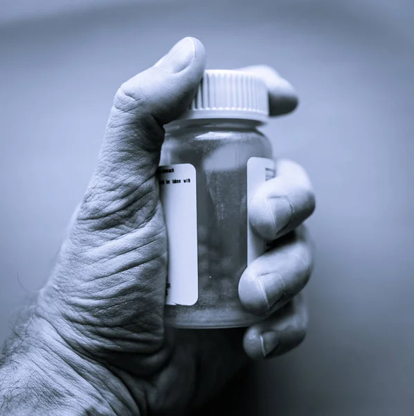 Man holds bottle of prescription pills in palm of hand. Health care concept. Medical concept. Addiction concept. Closeup.