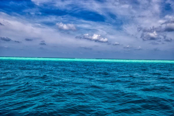 このユニークな写真は モルディブの背景に深い青色と島を回すターコイズブルーの海の景色を示しています — ストック写真