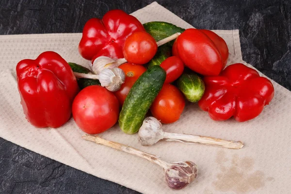 Lada merah, mentimun, tomat dan bawang putih pada handuk dapur — Stok Foto