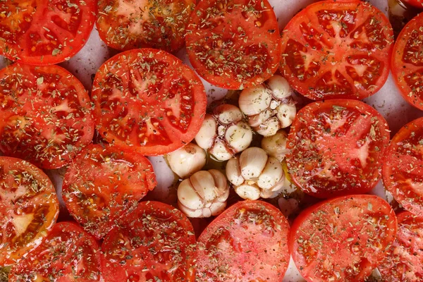 Tomat irisan merah, ditaburi dengan rempah-rempah dan bawang putih di bak — Stok Foto