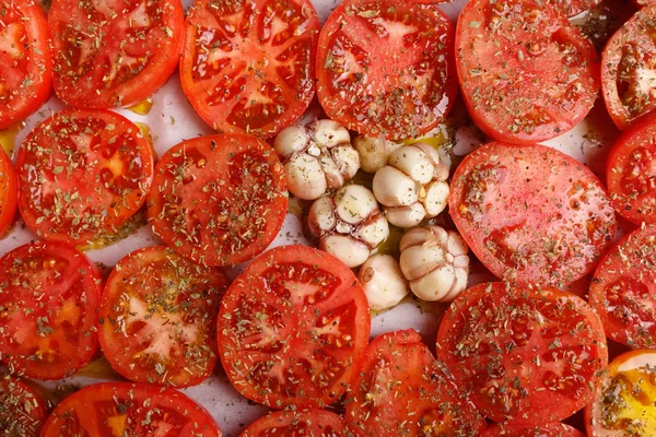 Tomat irisan merah, ditaburi dengan rempah-rempah dan bawang putih di bak — Stok Foto