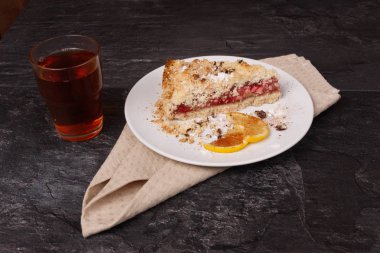 Kek ve limon beyaz tabakta, çay ise cam bardakta.