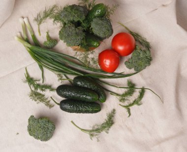 Bir kumaşta yeşil soğan, salatalık, domates, brokoli ve dereotu.