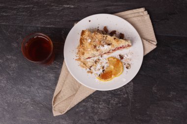 Kek ve limon beyaz tabakta, çay ise cam bardakta.