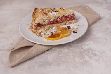 Küçük kek ve limon beyaz bir tabakta hafif bir sırt çantasında havlunun üzerinde.