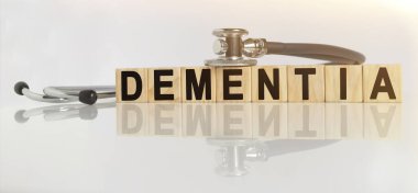 DEMENTIA kelime ahşap küpler üzerinde, küpler yansıtıcı beyaz bir yüzey üzerinde durur, küpler üzerinde - bir stetoskop. Tıp konsepti