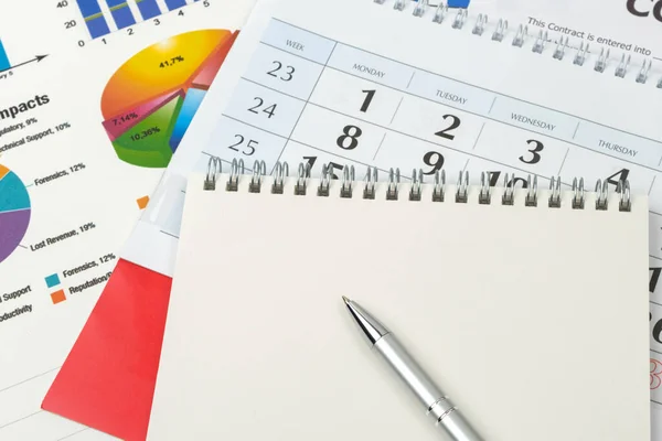 Business goal concept. Business accessory, graph charts, calendar, notebook and pen on the table