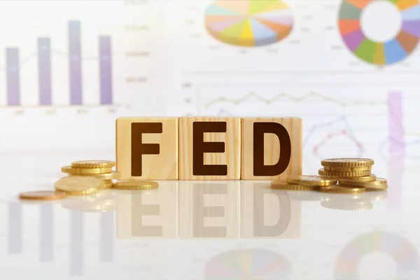Federal Rezerv. Tahta küplerle beslenen sözcük, yansıtıcı yüzeyde duran küpler, arka planda bir iş diyagramı. İş ve finans kavramı