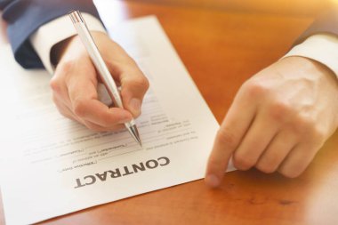 Ofis masasında oturan bir işadamı imzaya odaklı bir sözleşme imzalıyor. İş konsepti