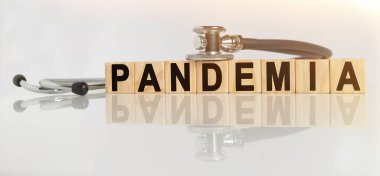 PandeMIA kelime ahşap küpler üzerinde, küpler yansıtıcı beyaz bir yüzey üzerinde durur, küpler üzerinde - bir stetoskop. Tıp konsepti