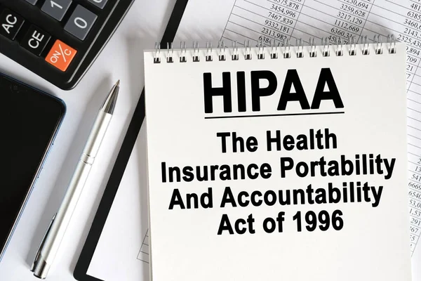 桌上放着一个智能手机 一个计算器和一个笔记本 上面写着 Hipaa 1996年 健康保险可携带性和责任法 — 图库照片