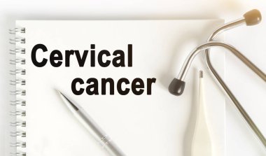 Masanın üzerinde stetoskop, termometre, kalem ve üzerinde rahim ağzı kanseri yazan bir defter var. Tıp konsepti.