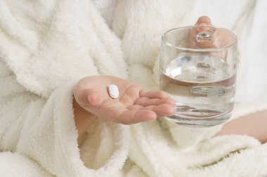 Kızın biri ilaçların olduğu masadan termometre alıyor. Tıbbi konsept.