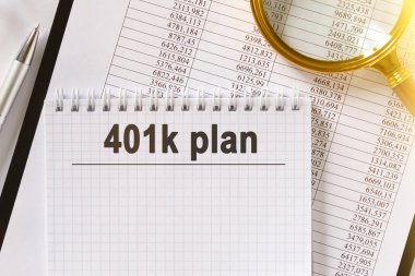 Masanın üzerinde mali raporlar, bir kalem, bir büyüteç ve üzerinde 401k yazılı bir defter var. İş ve finans kavramı.