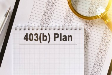 Masanın üzerinde mali raporlar, bir kalem, bir büyüteç ve üzerinde 403b Planı yazan bir defter var. İş ve finans kavramı.