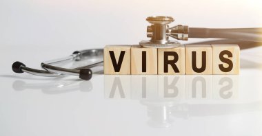VIRUS kelime ahşap küpler, küpler yansıtıcı beyaz bir yüzey üzerinde durur, küpler - bir stetoskop. Tıp konsepti