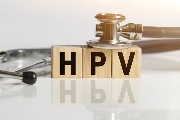 HPV kelime ahşap küpler üzerinde, küpler yansıtıcı beyaz bir yüzey üzerinde, küpler üzerinde - bir stetoskop. Tıp konsepti