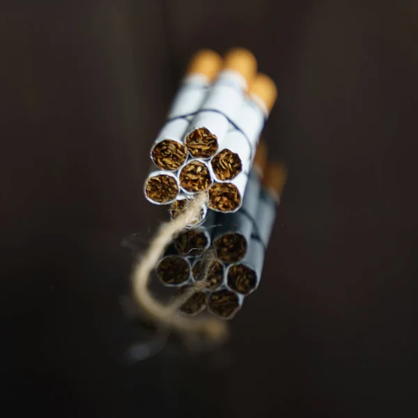 医学的概念是与吸烟作斗争 香烟被扭曲成在黑色反射面上有长丝的炸药止回阀 — 图库照片