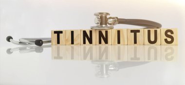 TINNITUS kelime ahşap küpler, küpler yansıtıcı beyaz bir yüzey üzerinde durur, küpler - bir stetoskop. Tıp konsepti
