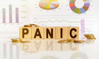 PANIC kelime ahşap küpler üzerinde, küpler yansıtıcı bir yüzey üzerinde duruyor, arka planda bir iş diyagramı var. İş ve finans kavramı