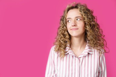 Genç ve güzel bir kadın boş fotokopi odasına bakarak düşünüyor. İzole edilmiş pembe arkaplan