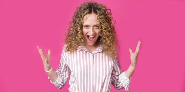 Kıvırcık saçlı bir kadın sevinçten avuçlarını kaldırıyor, birinden inanılmaz bir hediye aldığına seviniyor, yüksek sesle bağırıyor, çizgili bir gömlek giyiyor. Mor bir arka planda izole edilmiş..