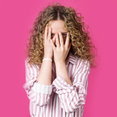 Utangaç, çekingen ya da utangaç güzel bir kızın portresi. Yüzü kaplayan ve parmaklarıyla röntgenleyen, kameraya bakan, meraklı. Vücut dili