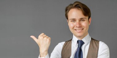 Sağ elini gösteren bir iş adamının duygusal portresi. Gri arka plan. İş ve finans kavramı